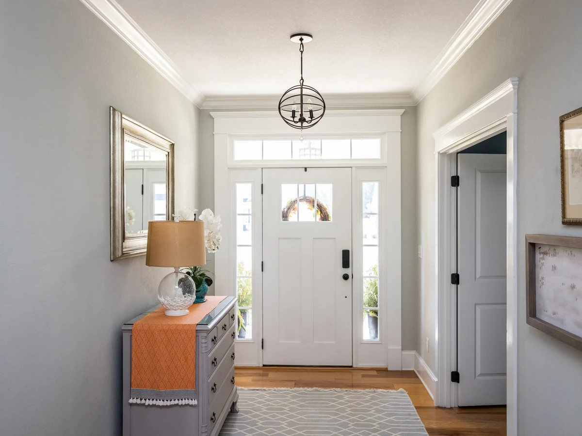 hallway-painting-grey-entrance-hallway-cotswolds-decorators A grey and white entrance hallway with a chandelier, white front door and painted walls