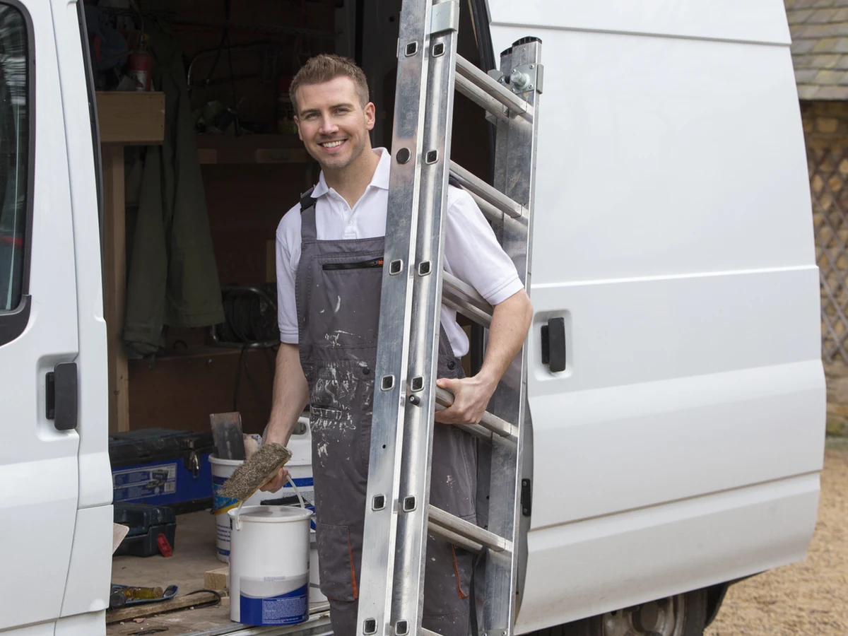 painting-decorating-smiling-decorator-ladder-cotswolds-decorators Smiling decorator on ladder working on a house in Nailsworth, Cotswolds Decorators